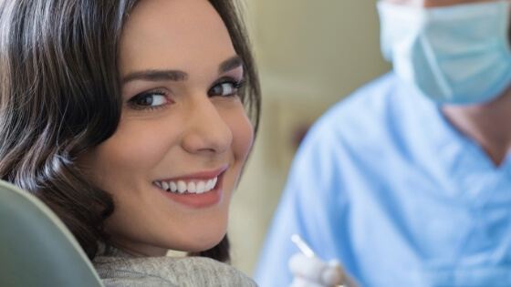 Woman smiling during dental checkup to prevent dental emergencies