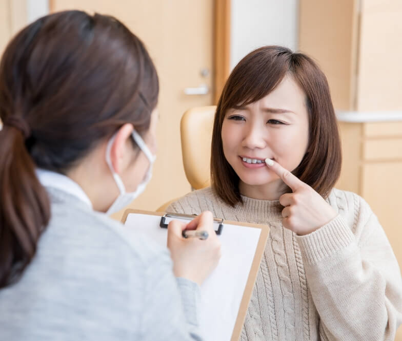 Woman pointing to smile during gum disease therapy visit