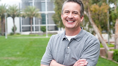 man with crossed arms smiling outside