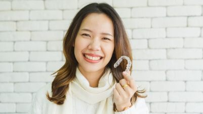 Smiling woman holding oral appliance for T M J therapy