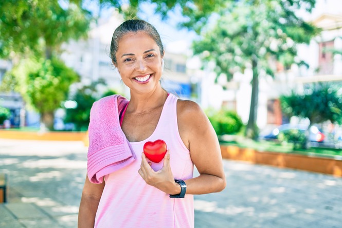 older woman smiling while holding heart